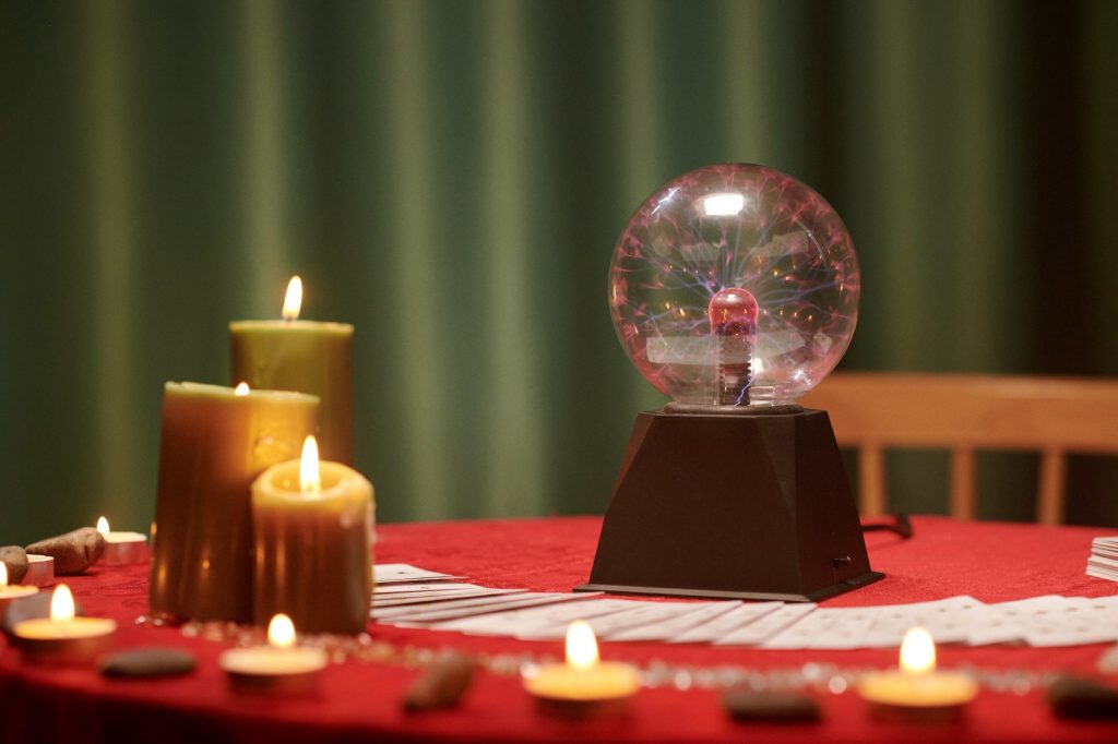 Crystal ball and burning candles on table of seer